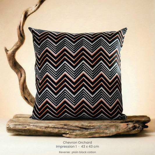 Decorative cushion in orange, black and white on driftwood.