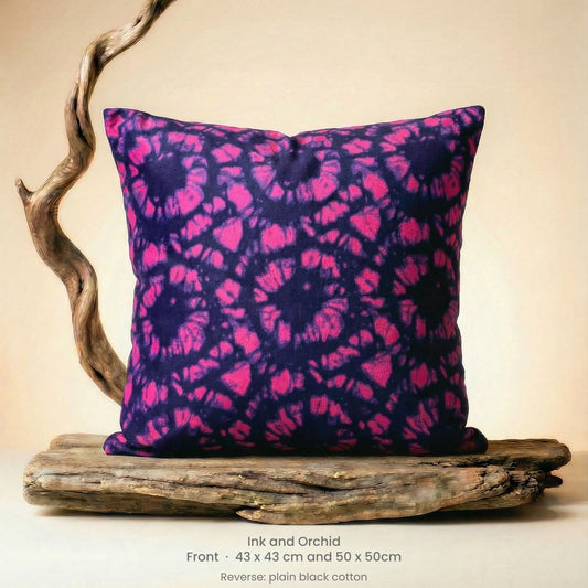 Tie-dye pillow with pink and purple pattern on driftwood