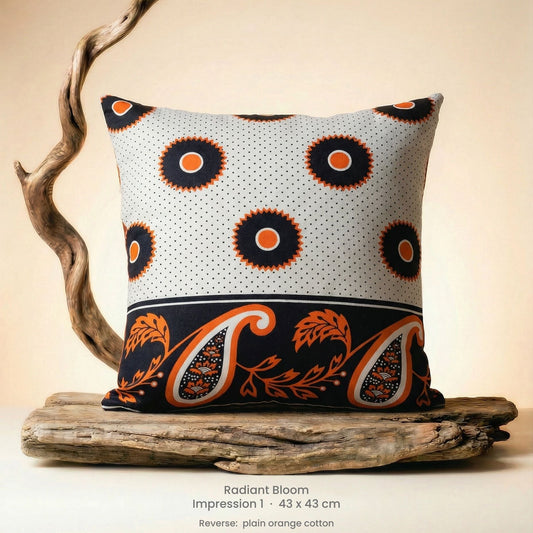 Decorative cushion with orange, black and white pattern on driftwood with a neutral background.
