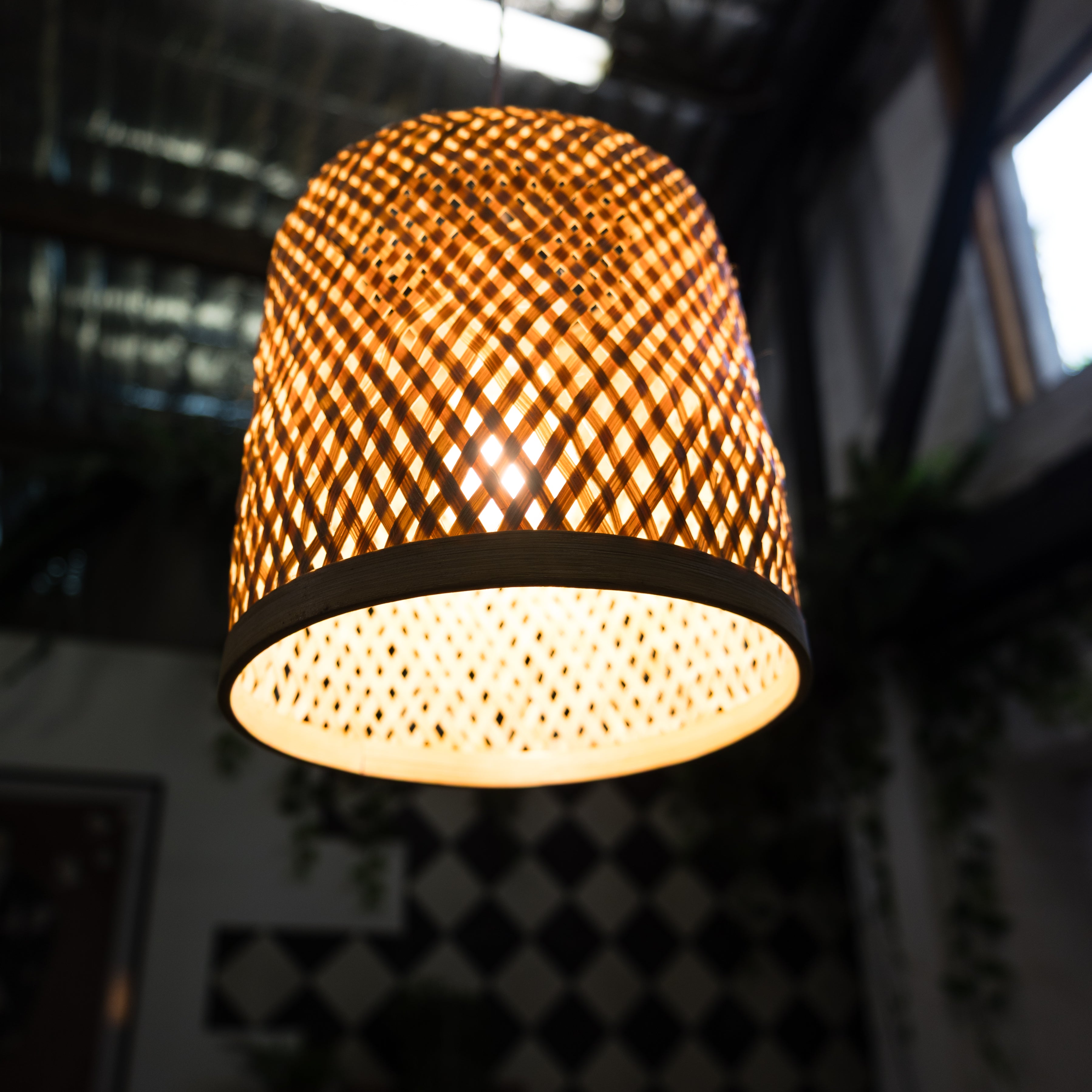 Woven rattan lampshade with a warm glow against a blurred background