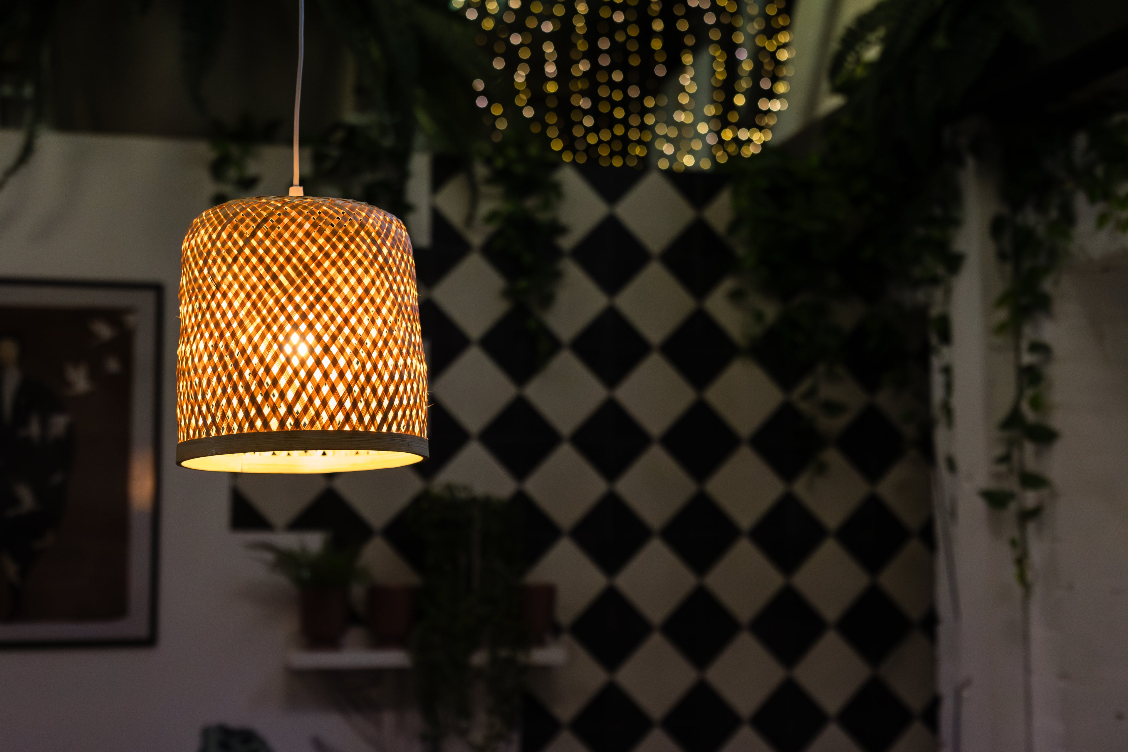 Woven pendant light hanging in a room with a black and white checkered wall.