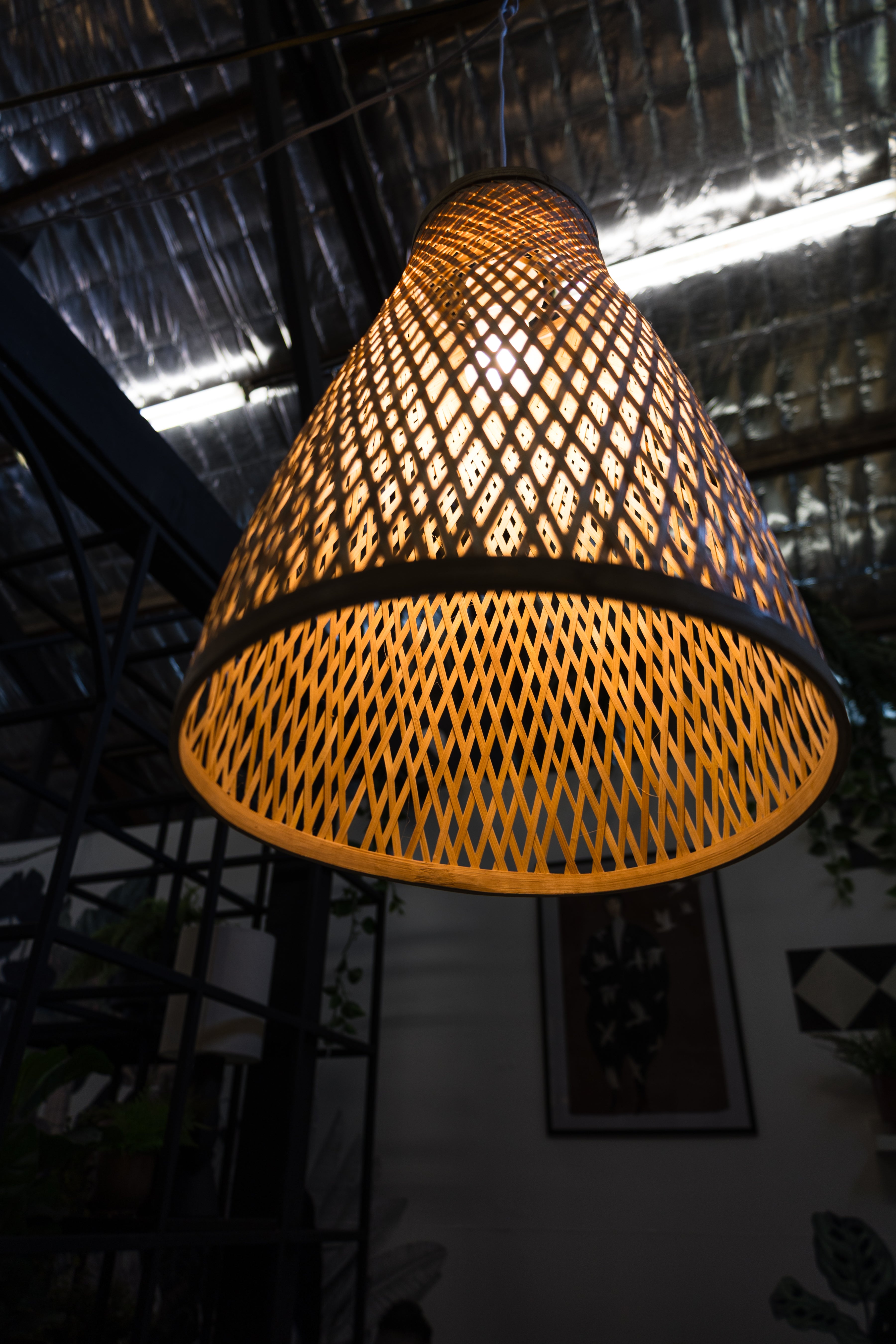 Woven lampshade hanging from a ceiling in a dimly lit room.