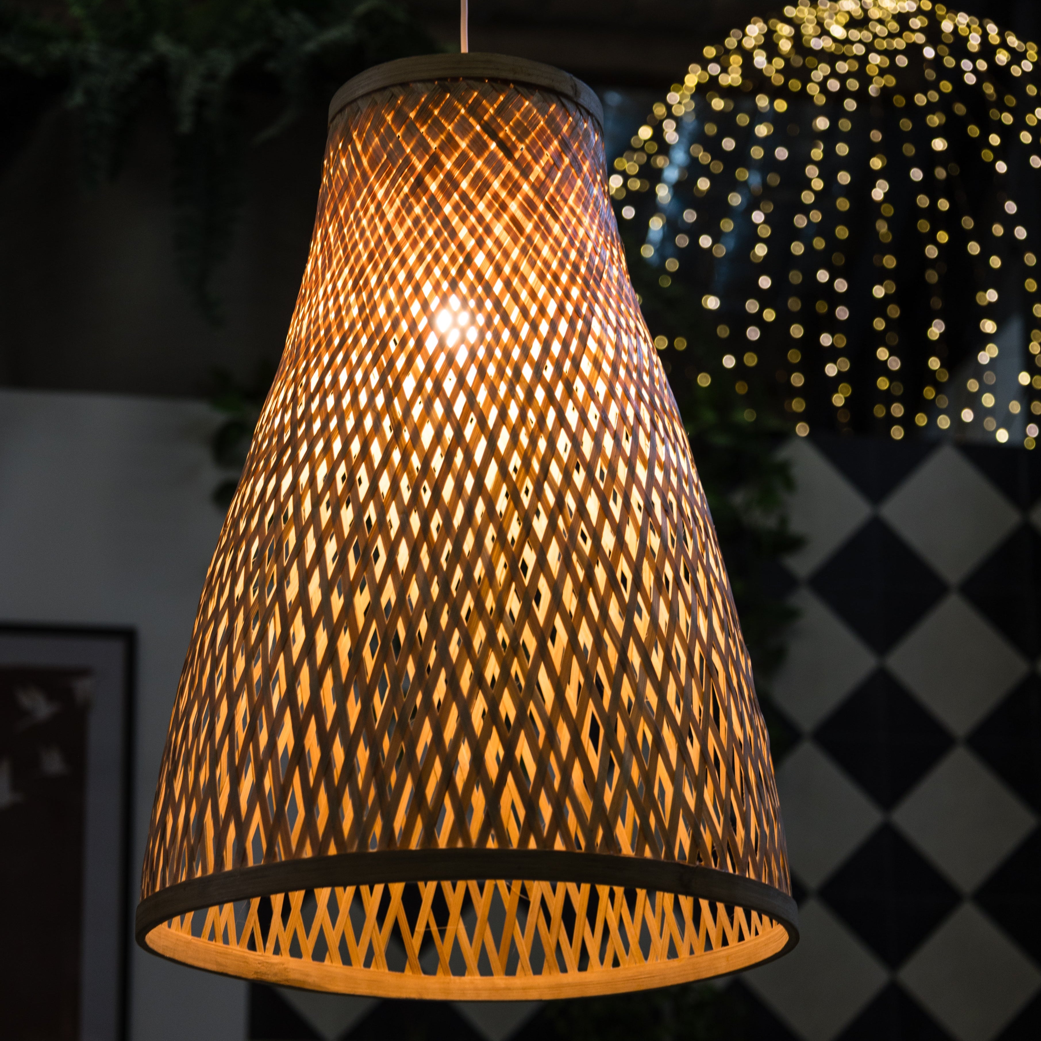 Woven lampshade hanging against a dark background with blurred lights