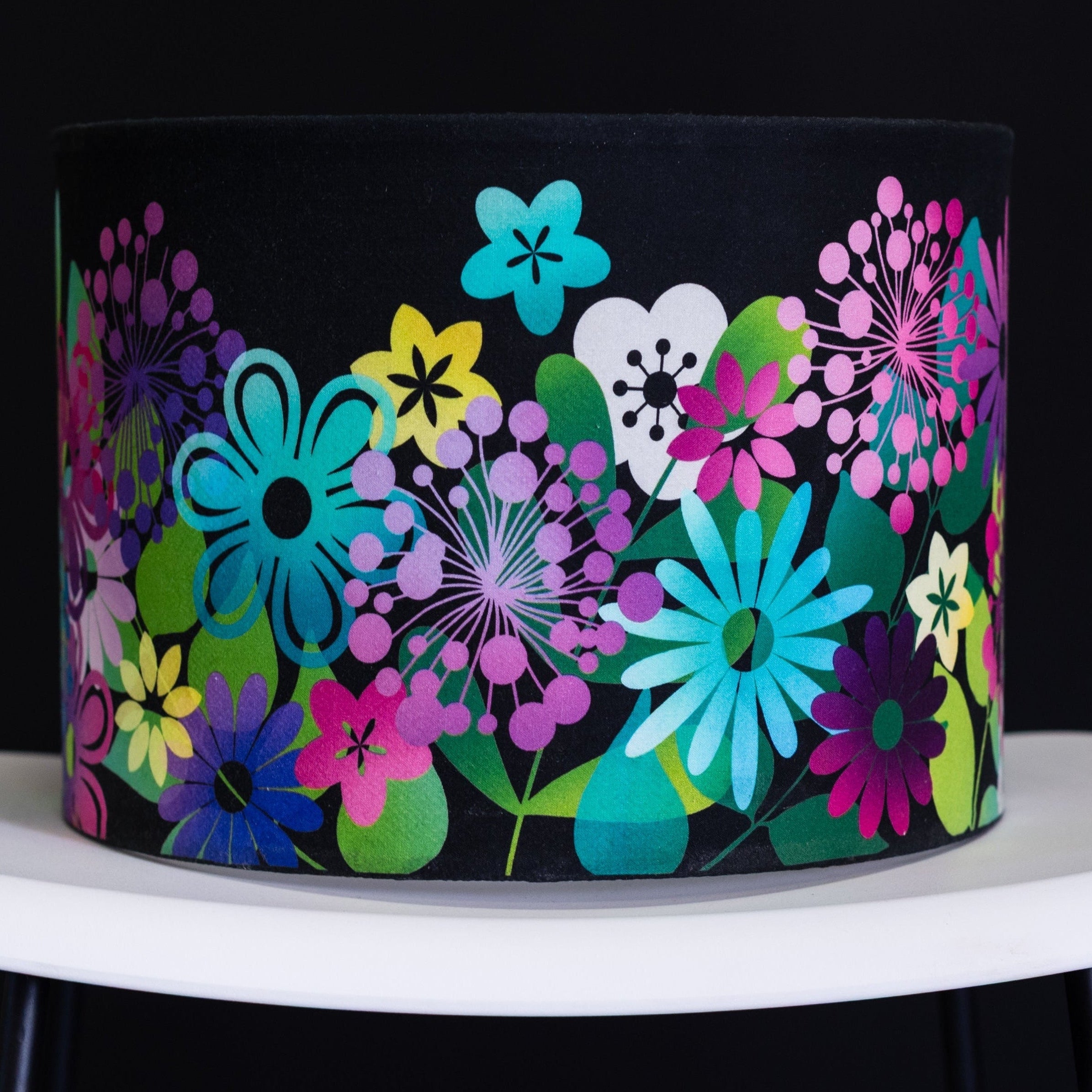 Colourful floral-patterned lampshade on a white surface with a black background