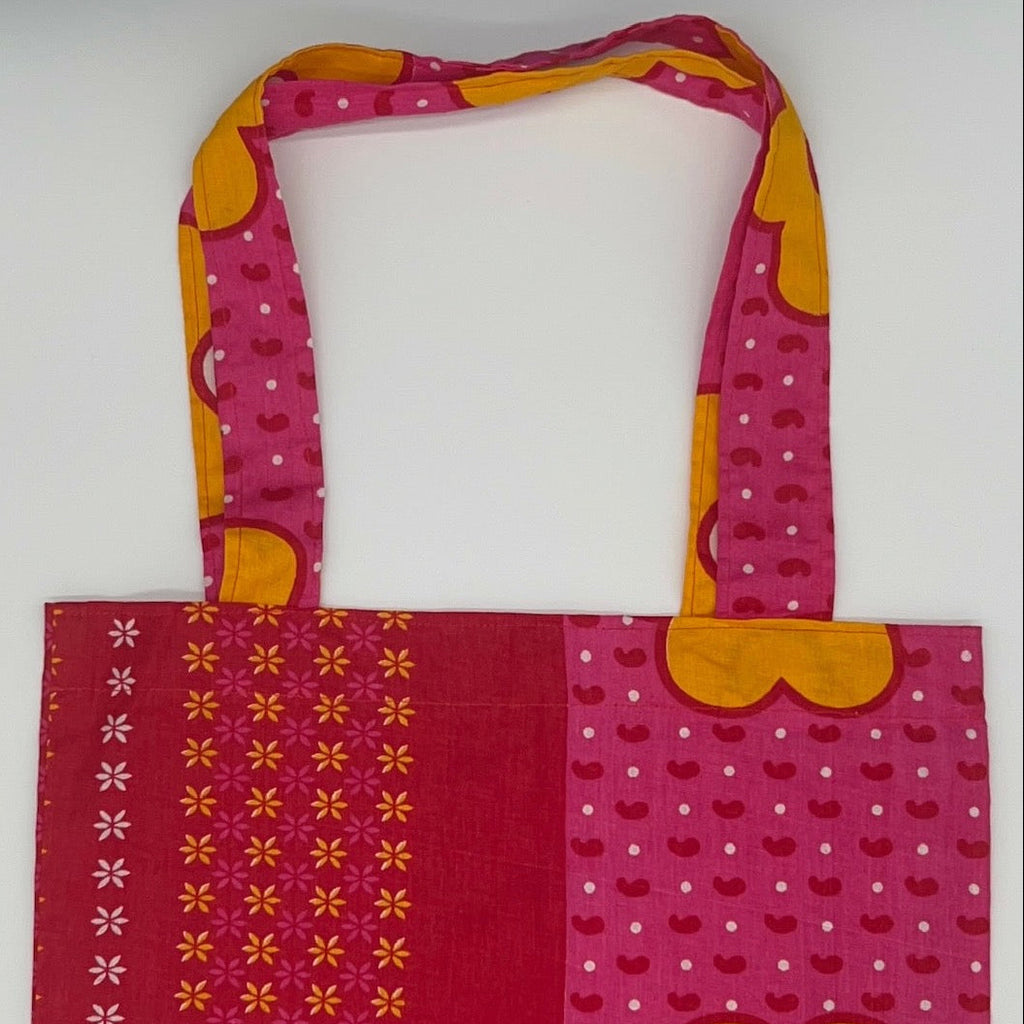Pink and red patterned tote bag with a yellow flower design on a white background