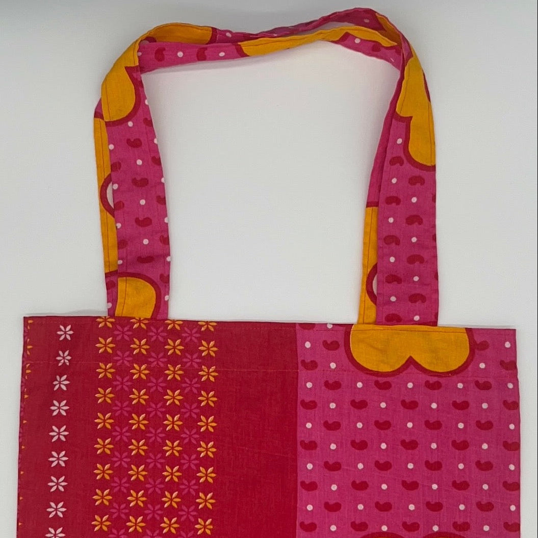 Pink and red patterned tote bag with a yellow flower design on a white background