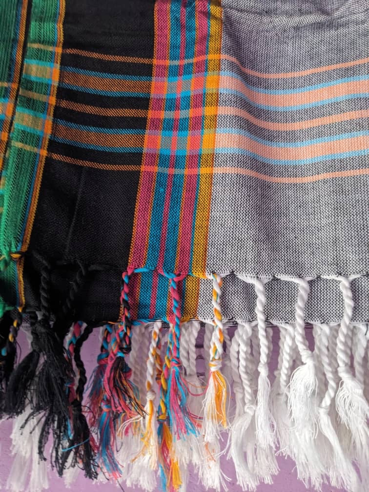 Grey, black and green plaid throw rug with tassels (closeup)