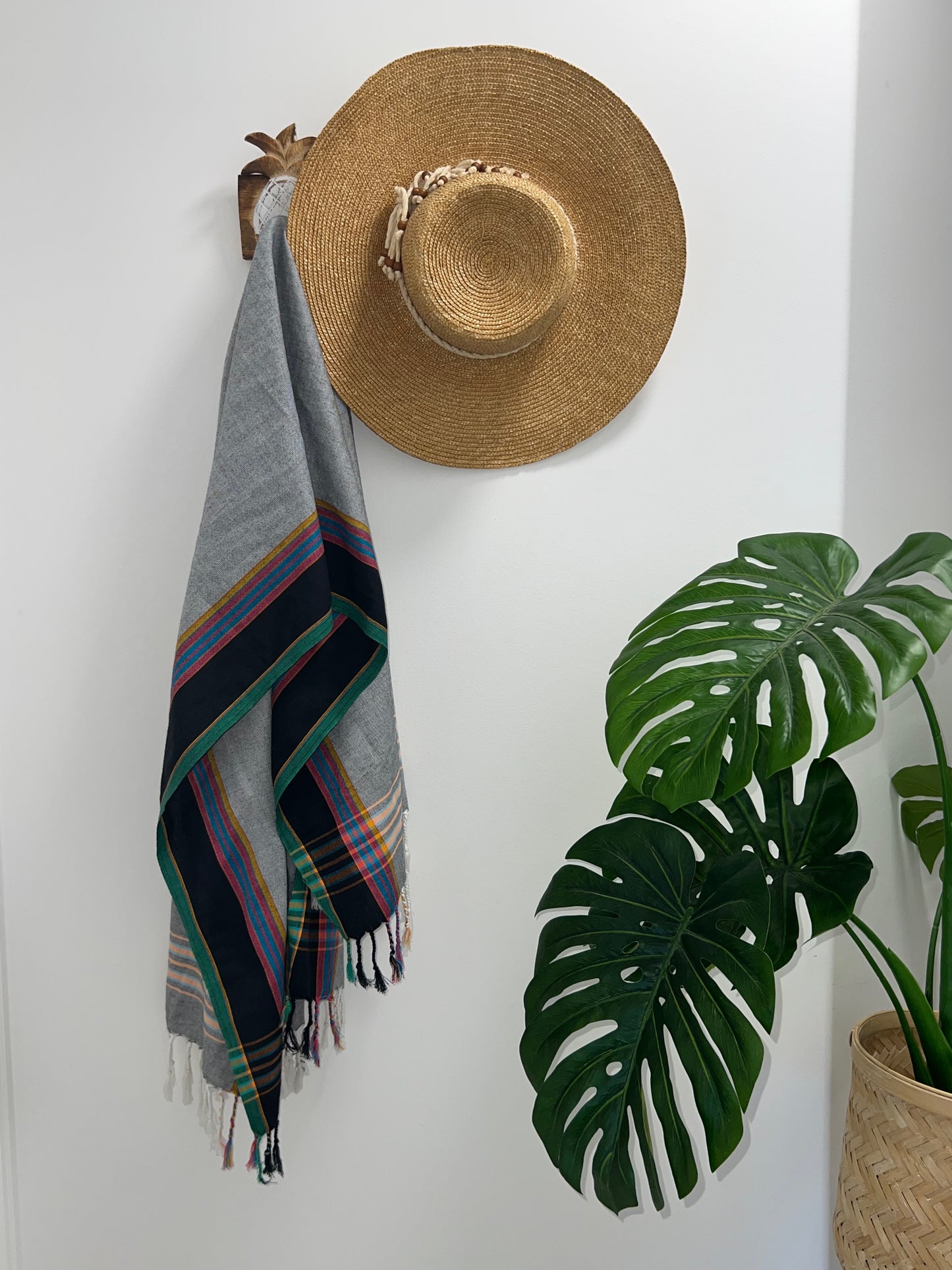 Grey, black and green throw rug on hook with straw hat