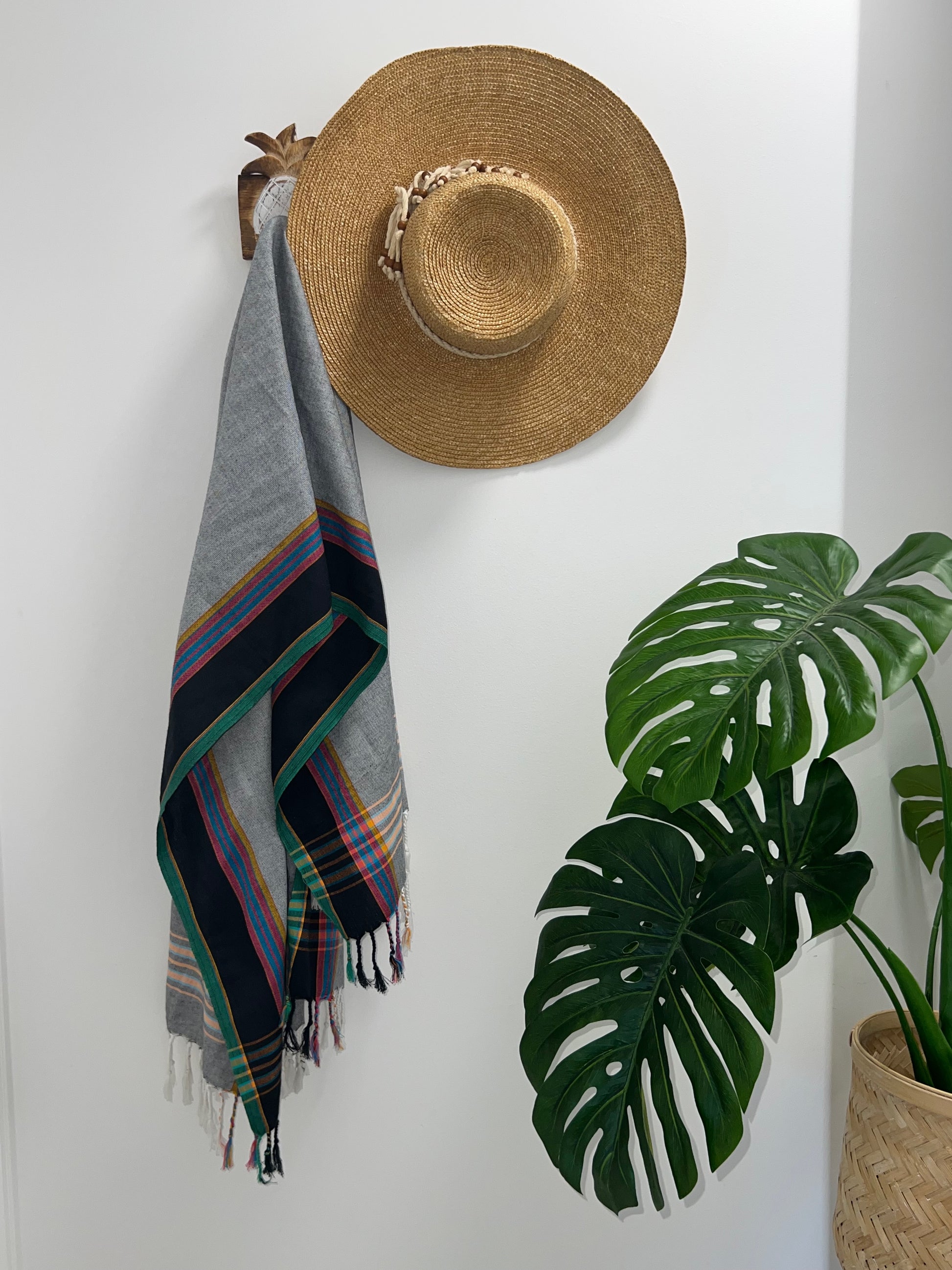 Grey, black and green throw rug on hook with straw hat