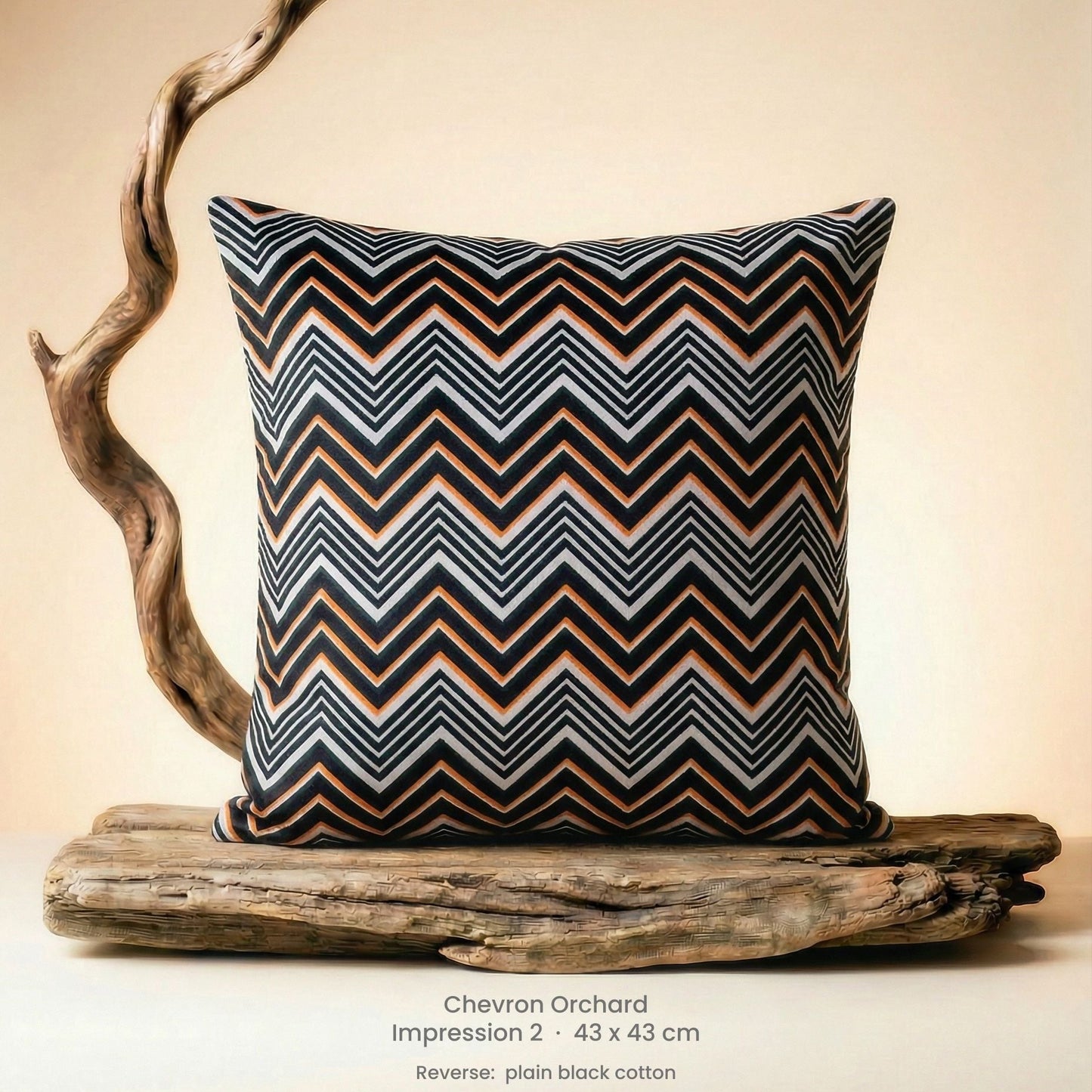 Decorative cushion in orange, black and white on driftwood.