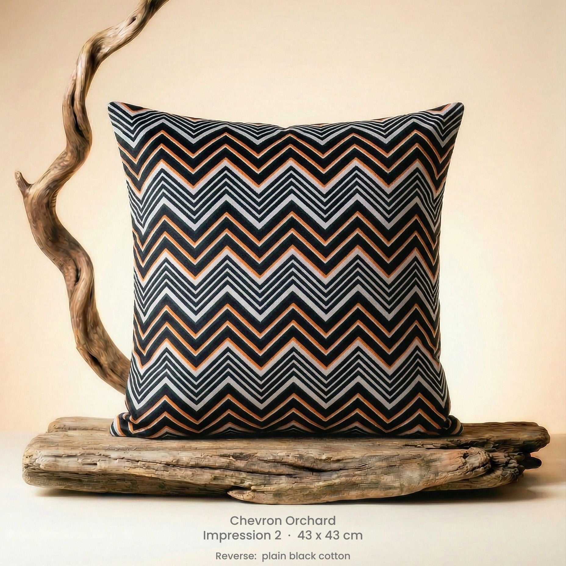Decorative cushion in orange, black and white on driftwood.