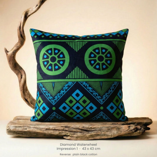 Decorative green, blue and black cushion with geometric pattern on driftwood with a neutral background.