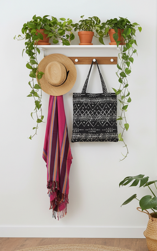 Flamingo Horizon kikoi and straw hat hanging on entryway rack with Zigzag Mudcloth tote and plants