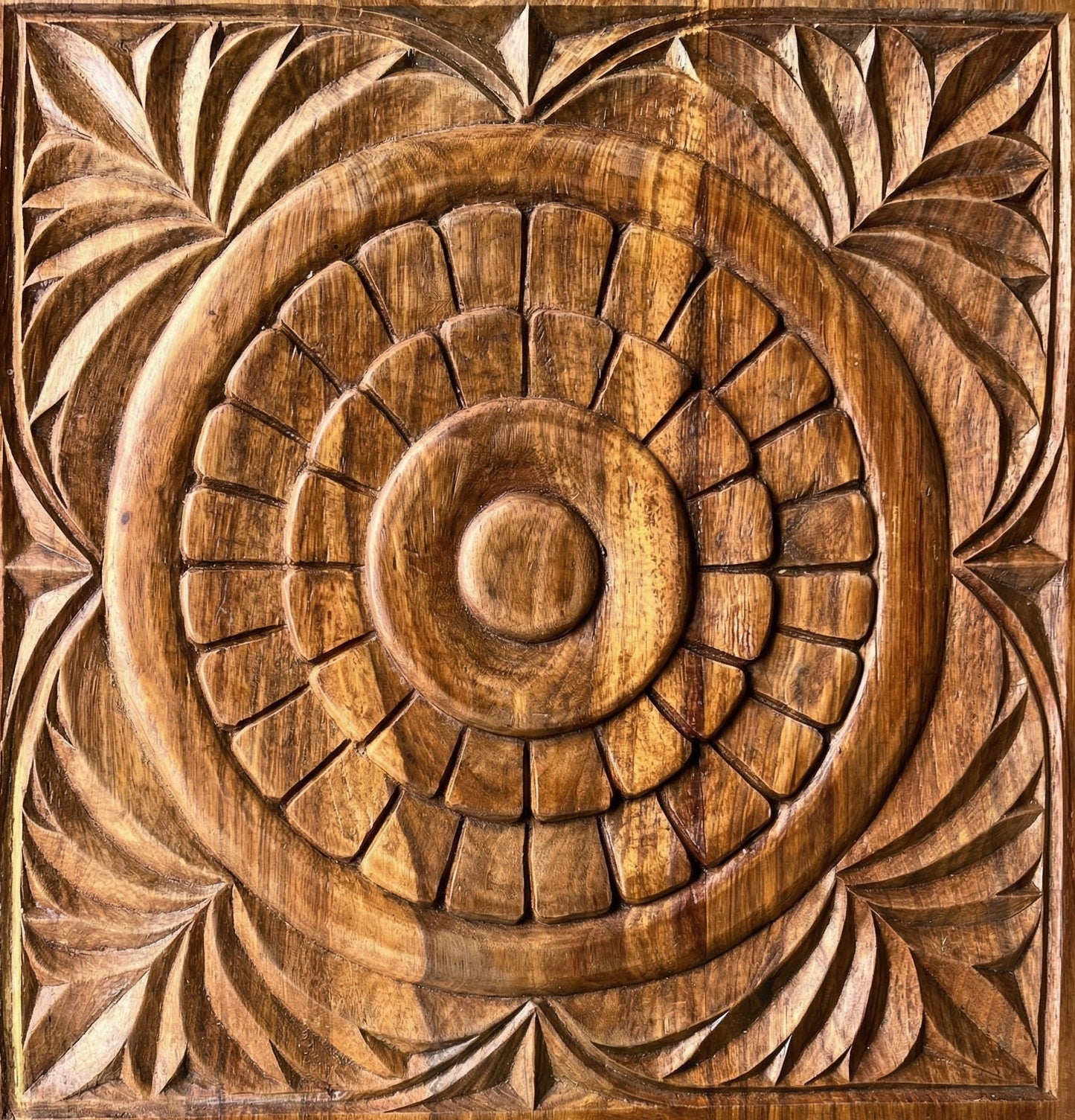 Wooden panel with intricate carvings of concentric circles and leaf patterns.