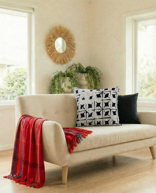 Beige sofa with decorative pillows and a red blanket in a bright living room.
