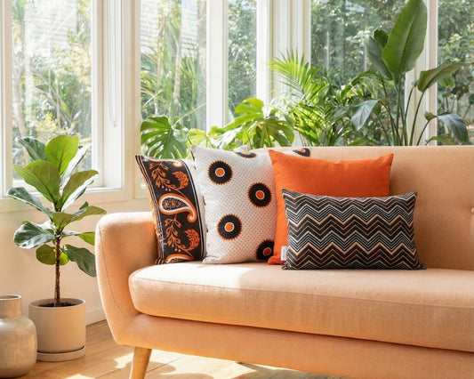 Light orange sofa with orange, black and white cushions in a sunlit room with large windows and plants.