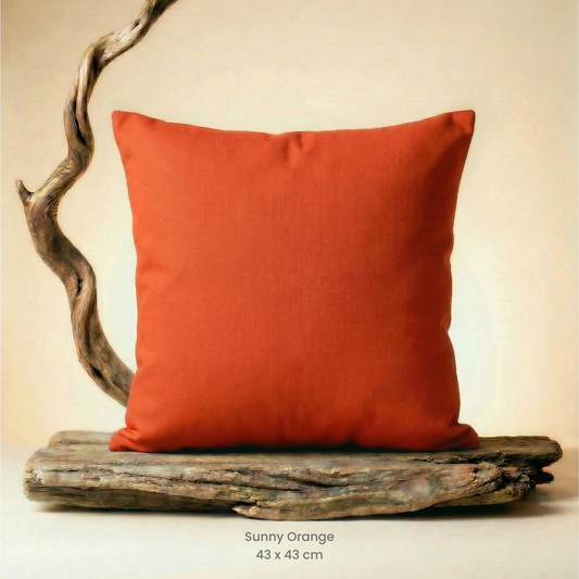 Sunny orange pillow on a wooden platform with a neutral background