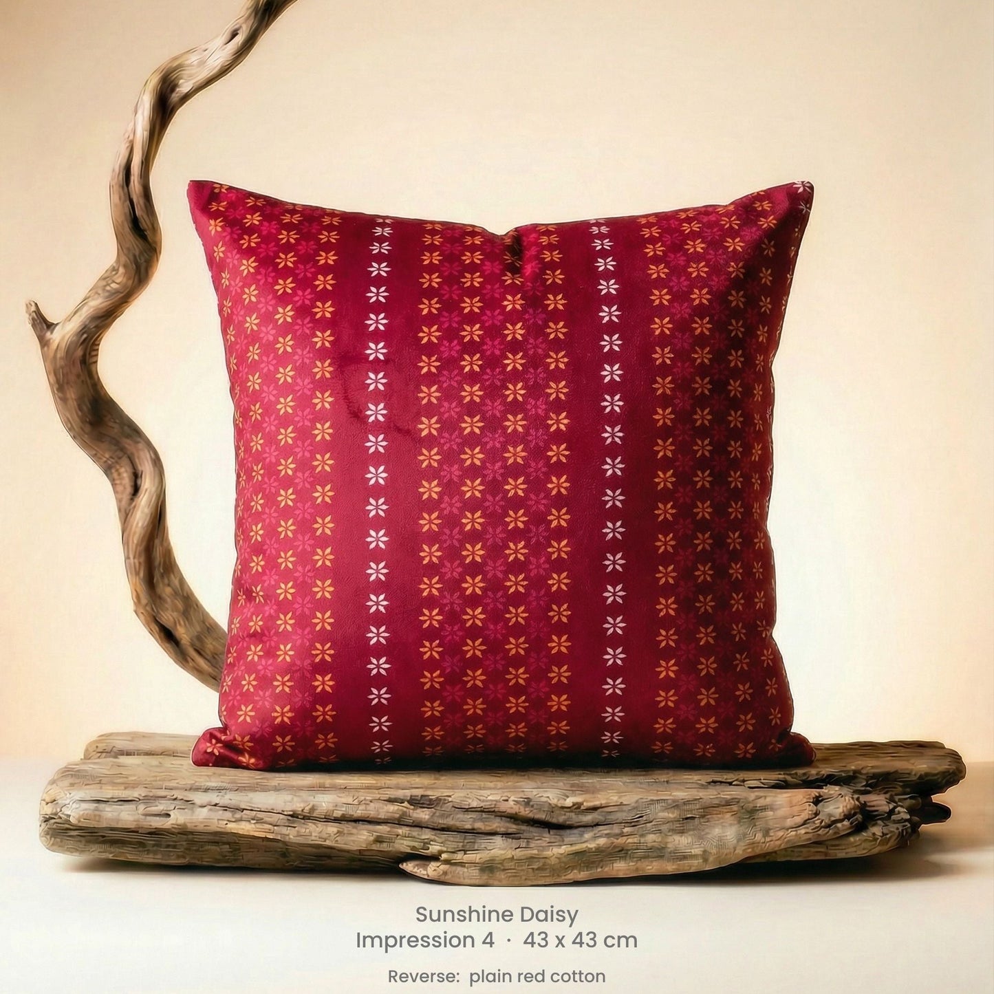 Decorative cushion with floral design in pink, red and yellow on driftwood.