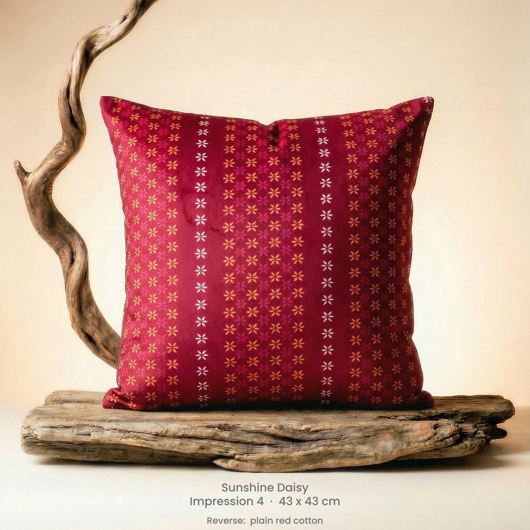 Decorative cushion with floral design in pink, red and yellow on driftwood.